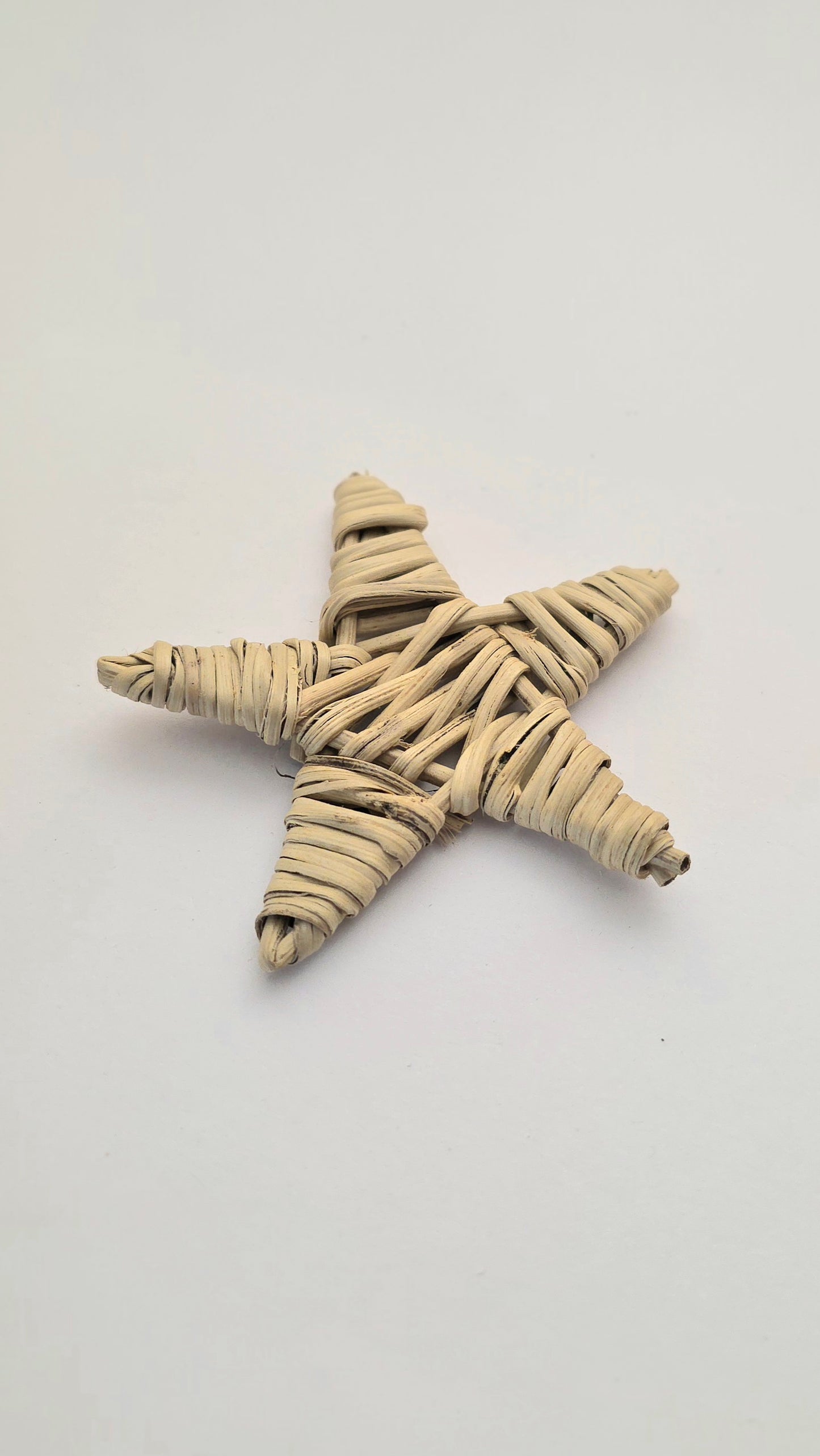 Star-shaped willow weave toy for birds on a light gray background